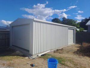Wide shed with gable roof, one large roller door in font, and medium roller door on the side.