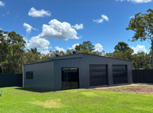 Barn style shed with three large roller doors, gable roof and skillon roof
