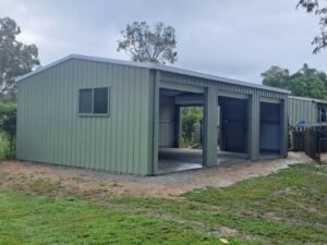 Wide, green utility shed with 4 roller doors pulled up