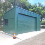 Peacock green shed with window, hinge door, and large sliding roller door. Built on cement slab.
