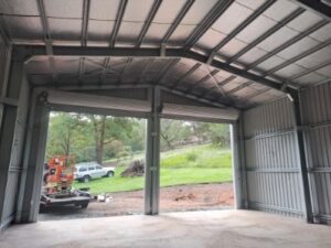 Inside of gable roof shed looking outside onto field with car
