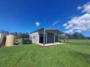 Shed in field of grass. Thee sliding roller doors.