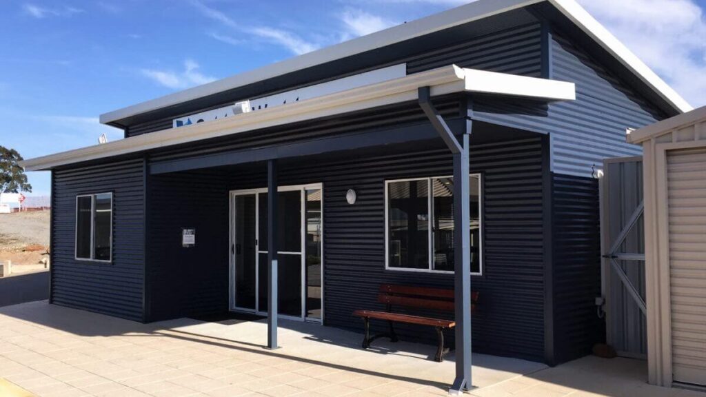 Dark blue colorbond shed with sliding glass door entry and window installed.